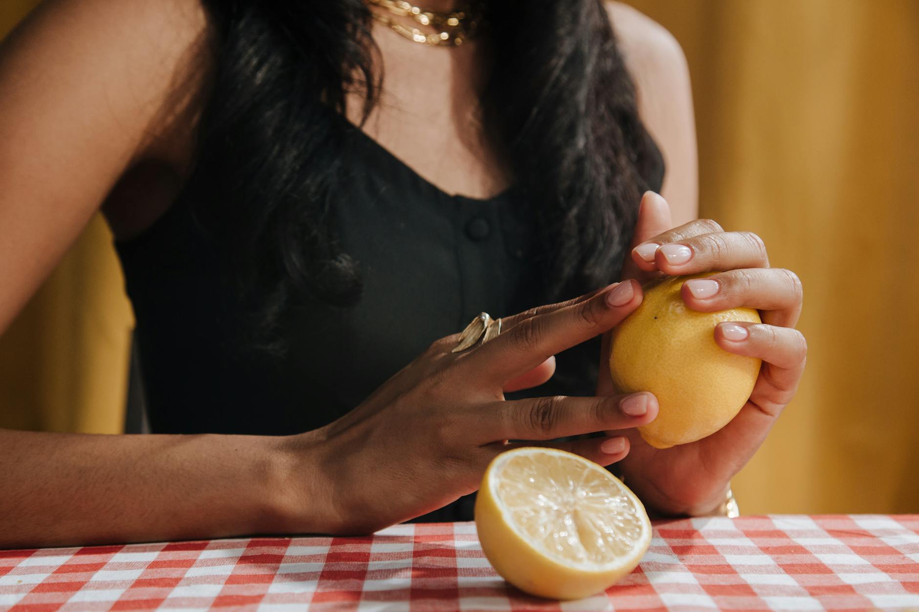 Woman holding fresh lemon at dining table, symbolizing natural pleasure without rush