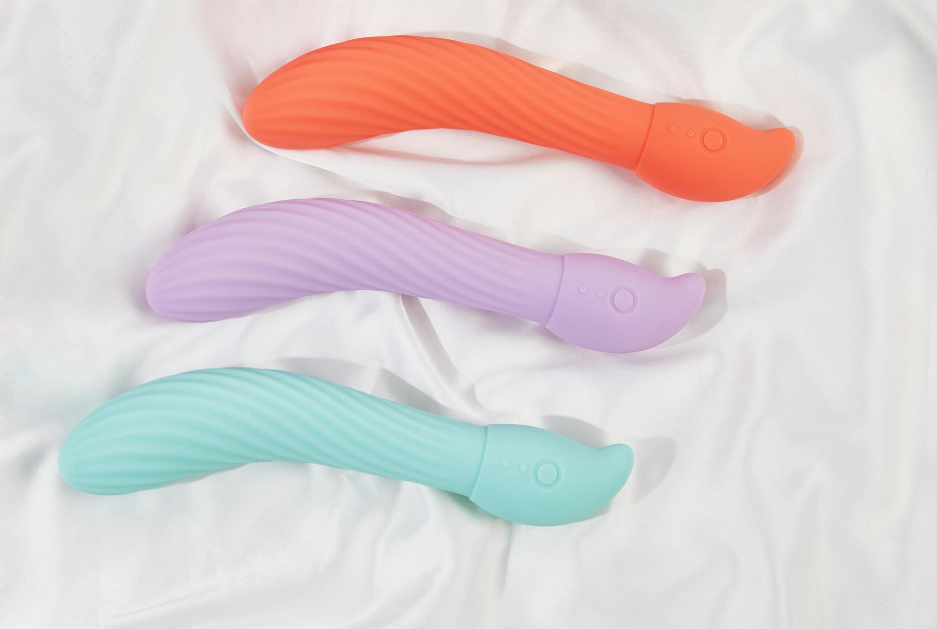 Three colorful lemon vibrators arranged on soft white fabric, showcasing their smooth clitoral design