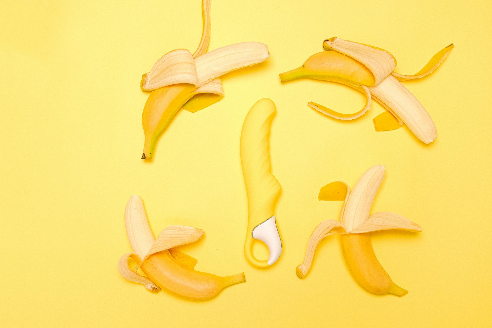 A yellow lemon vibrator surrounded by peeled bananas on a bright yellow background