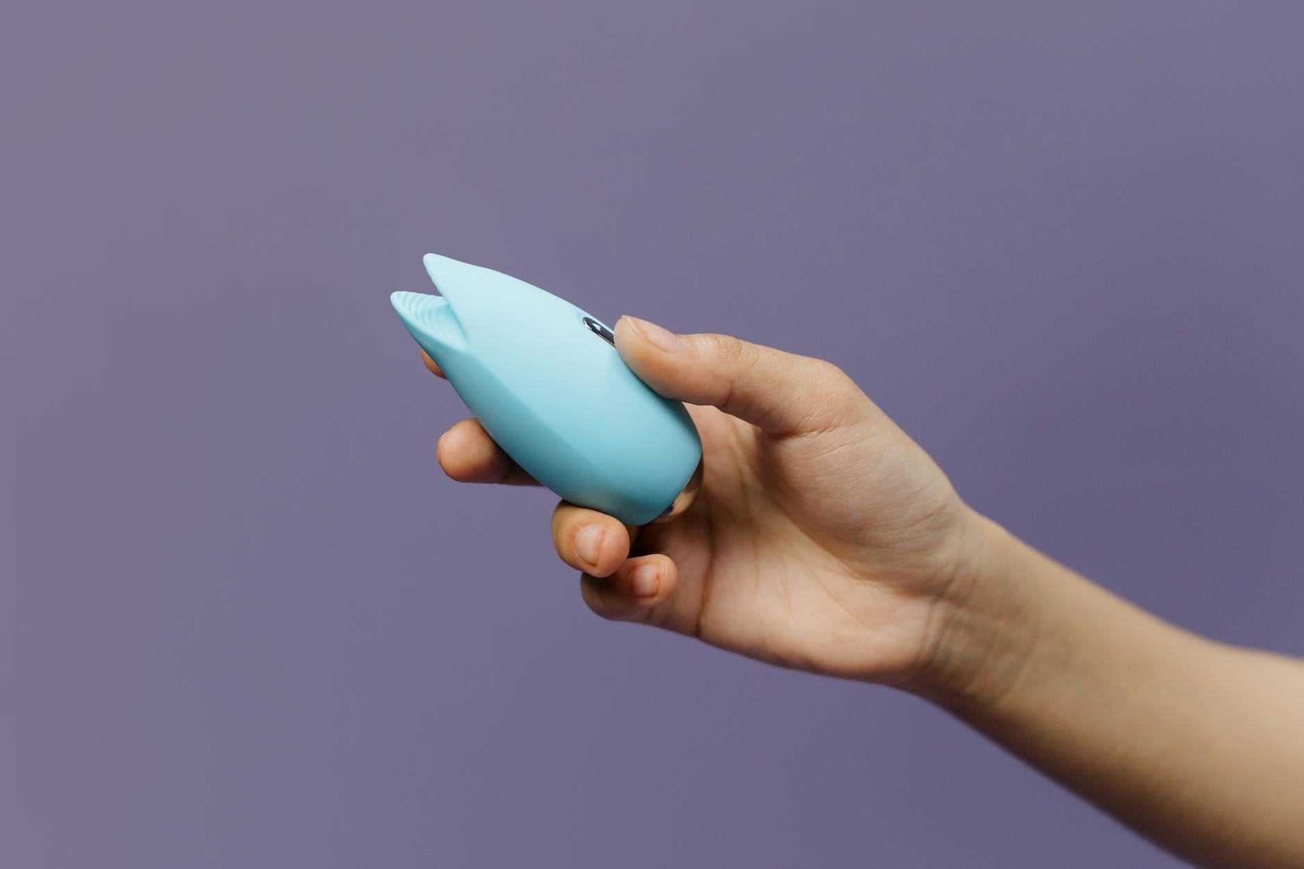 A lemon-colored silicone clitoral vibrator held in hand, symbolizing focused pleasure and clitoral stimulation.