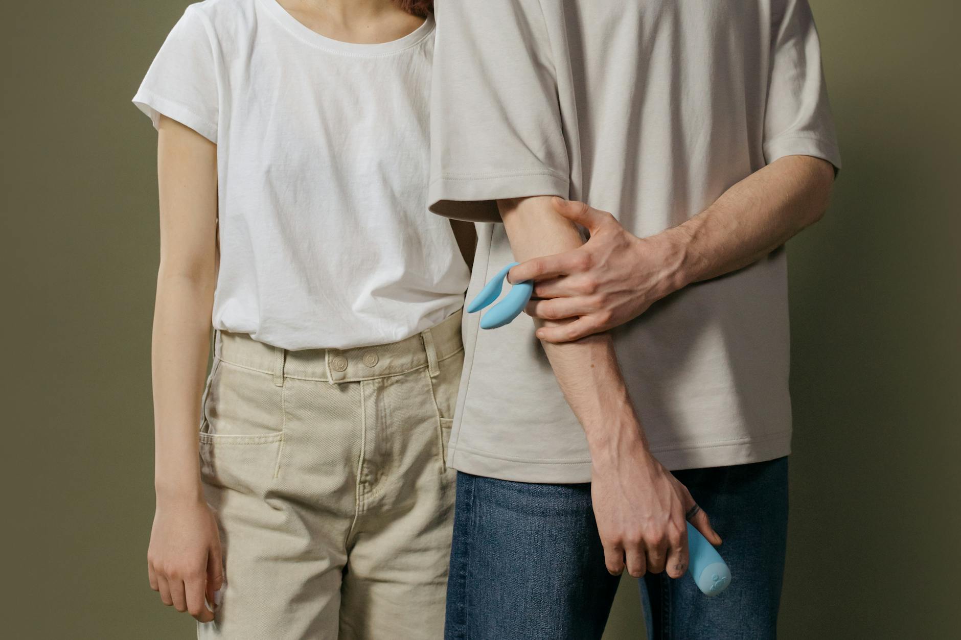 Hands holding a blue clitoral vibrator against a purple background, symbolizing intimate control and personal pleasure.