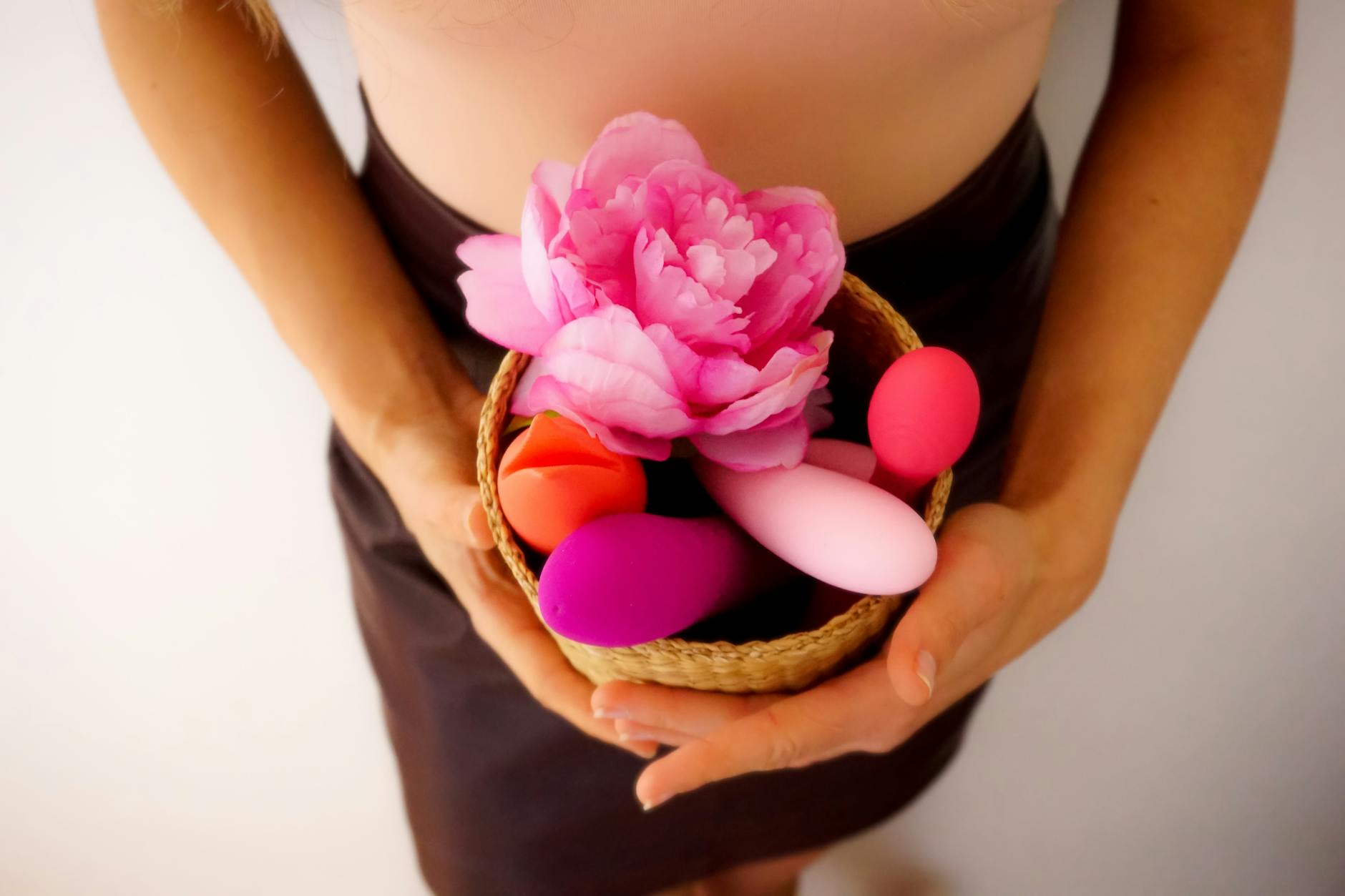A woman holds a vibrator thoughtfully, with art books nearby, suggesting intimate reflection